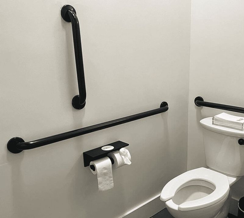 Matte black grab bars on light tile